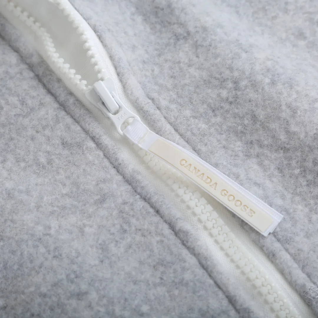 P780 Canada Goose Wool Fleece Hooded Jacket (Light Gray) The fabric is made of wool fleece fabric, which is mainly made of wool and mixed with a very small amount of spandex and polyester fiber. Wool is a core natural ingredient that provides unparalleled temperature regulation, antibacterial and anti-odor properties and a skin-friendly feel. The feeding of a small amount of spandex gives the fabric a certain degree of four-way elasticity, making it non-restrictive during daily activities. As the basis of fleece's structure, polyester fiber enhances the fabric's durability, wrinkle resistance and quick-drying properties. It contributes to the loft of the fleece and provides functions such as trapping air. The sleeves and hem are closed with 2×2 ribbing. Its strong elasticity can closely fit wrists and waists of different thicknesses, forming an effective 'seal' to prevent cold wind from blowing back. It can still maintain its original shape after repeated stretching and use, and is not easy to loose and deform. And the ribbed cuffs can convey a sense of design and enhance the visual beauty. The combination of hood design and elastic buckle improves warmth and windproof performance when worn. Size:S-M-L-XL